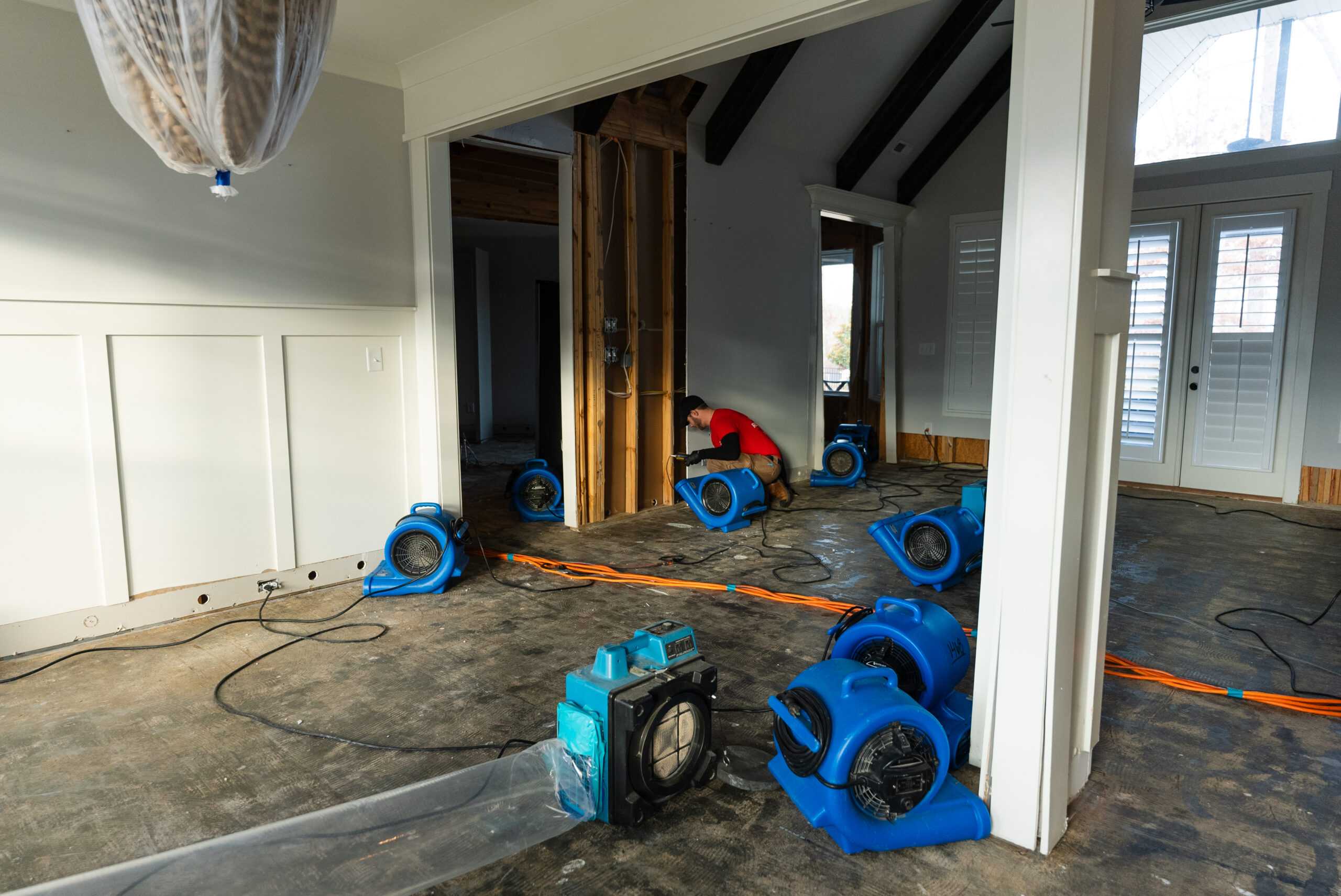 A technician and drying equipment inside a home undergoing water damage restoration